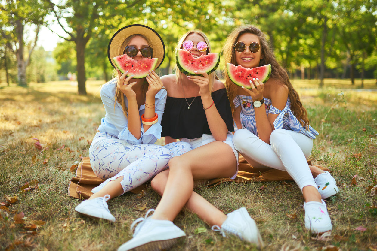 3 pretty ladies eating watermelon in the park